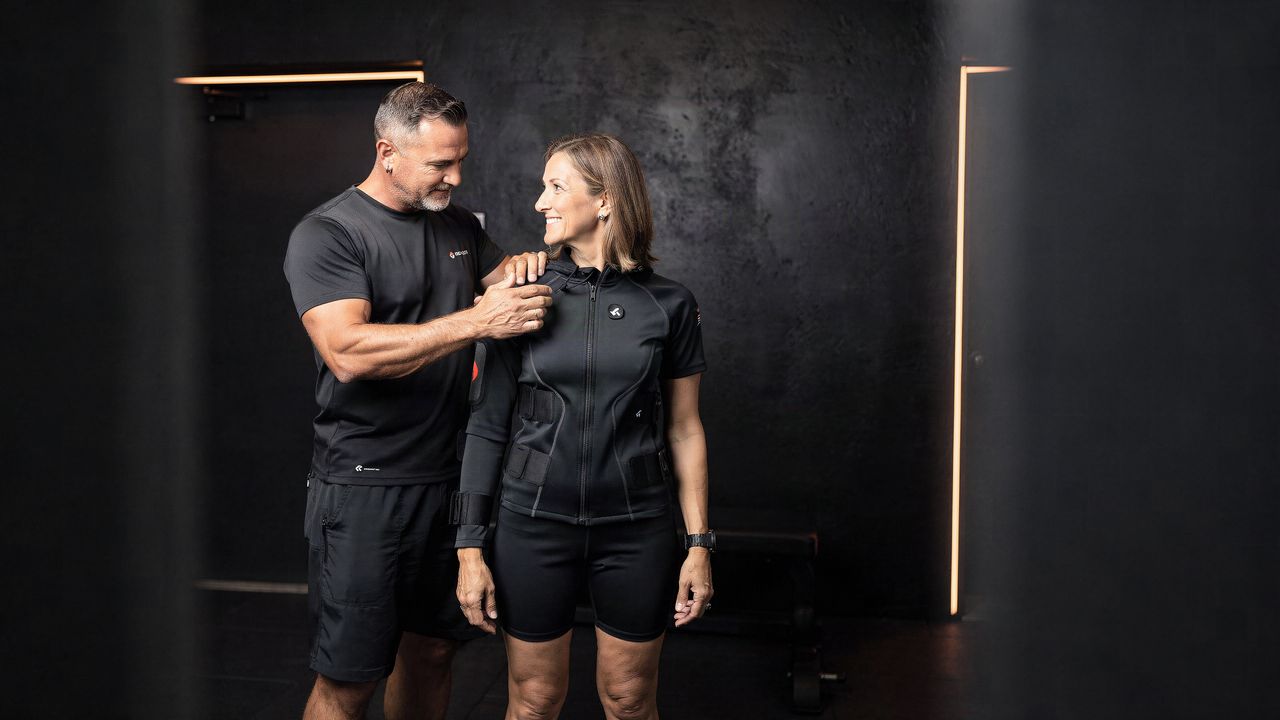 A trainer coaching a member through a held position, calm and unhurried